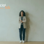 A portrait of a confident woman standing against a plain wall with a shadow composed of binary code patterns, symbolizing women's empowerment and leadership in technology and AI development at SocialLab.